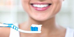 Smiling patient holding toothbrush with toothpaste on bristles